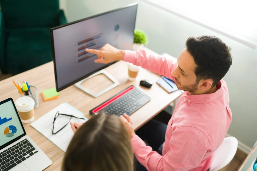 Business professionals reviewing SEO performance charts on a desktop monitor, representing the use of a React.js SEO Checklist for executive decision-making.