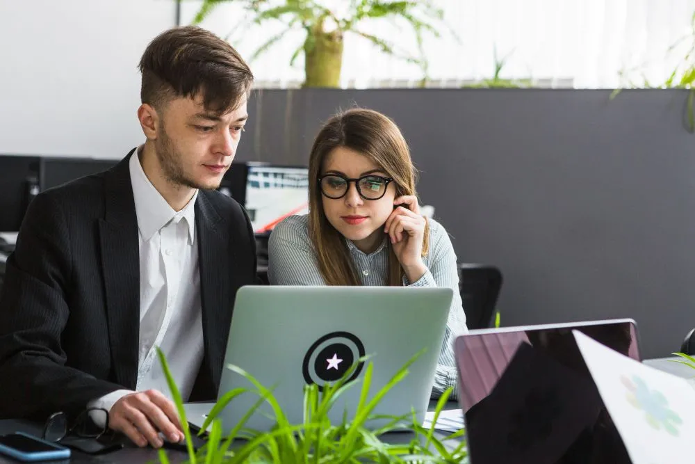 Enterprise professionals reviewing cloud infrastructure and delivery metrics on a laptop, illustrating the Benefits of DevOps as a Service for modern business operations.