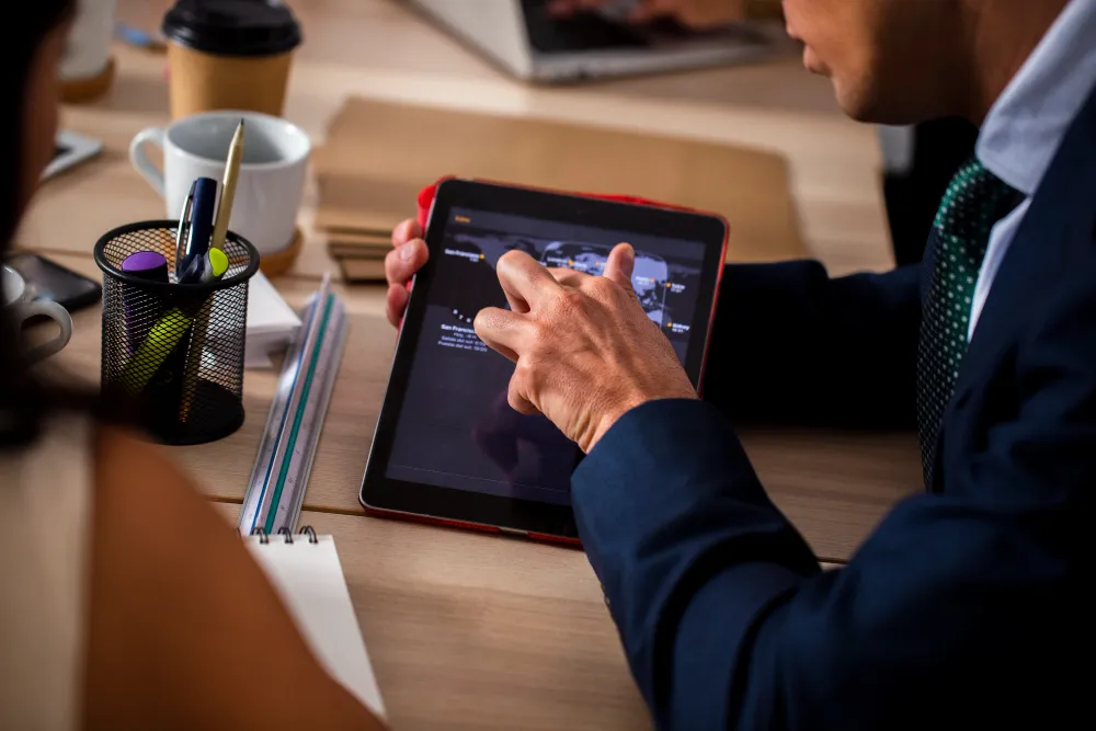 Enterprise professionals reviewing application performance metrics on a tablet, illustrating the use of a React.js Performance Checklist for optimizing AI-powered enterprise applications.